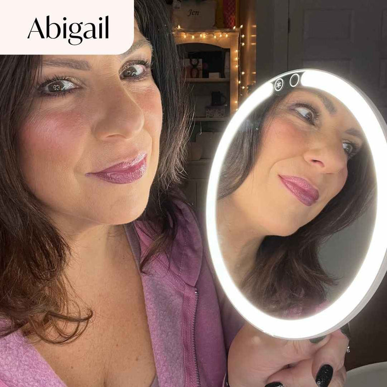 Abigail Lighted Compact in White Set up on desk and being used by model to apply lipstick