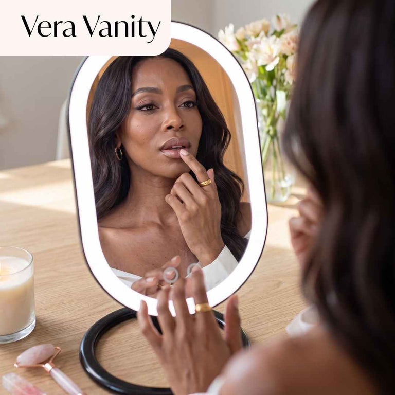 Abigail Lighted Compact in White Set up on desk and being used by model to apply lipstick