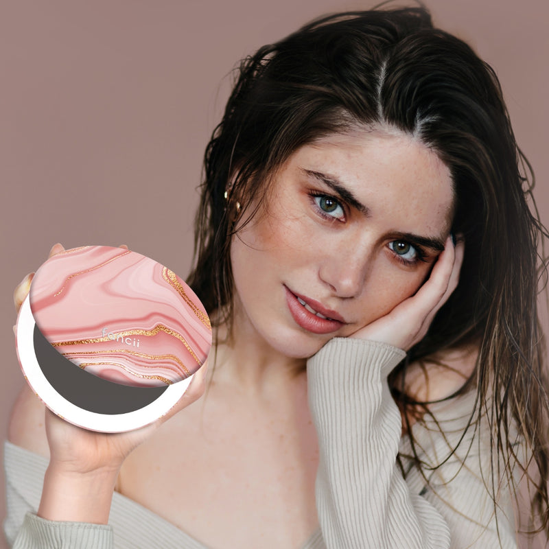 Taylor Lighted Compact Mirror with 10x Magnifying by Fancii & Co. open and lit up held by model in MARBLE ROSÈ